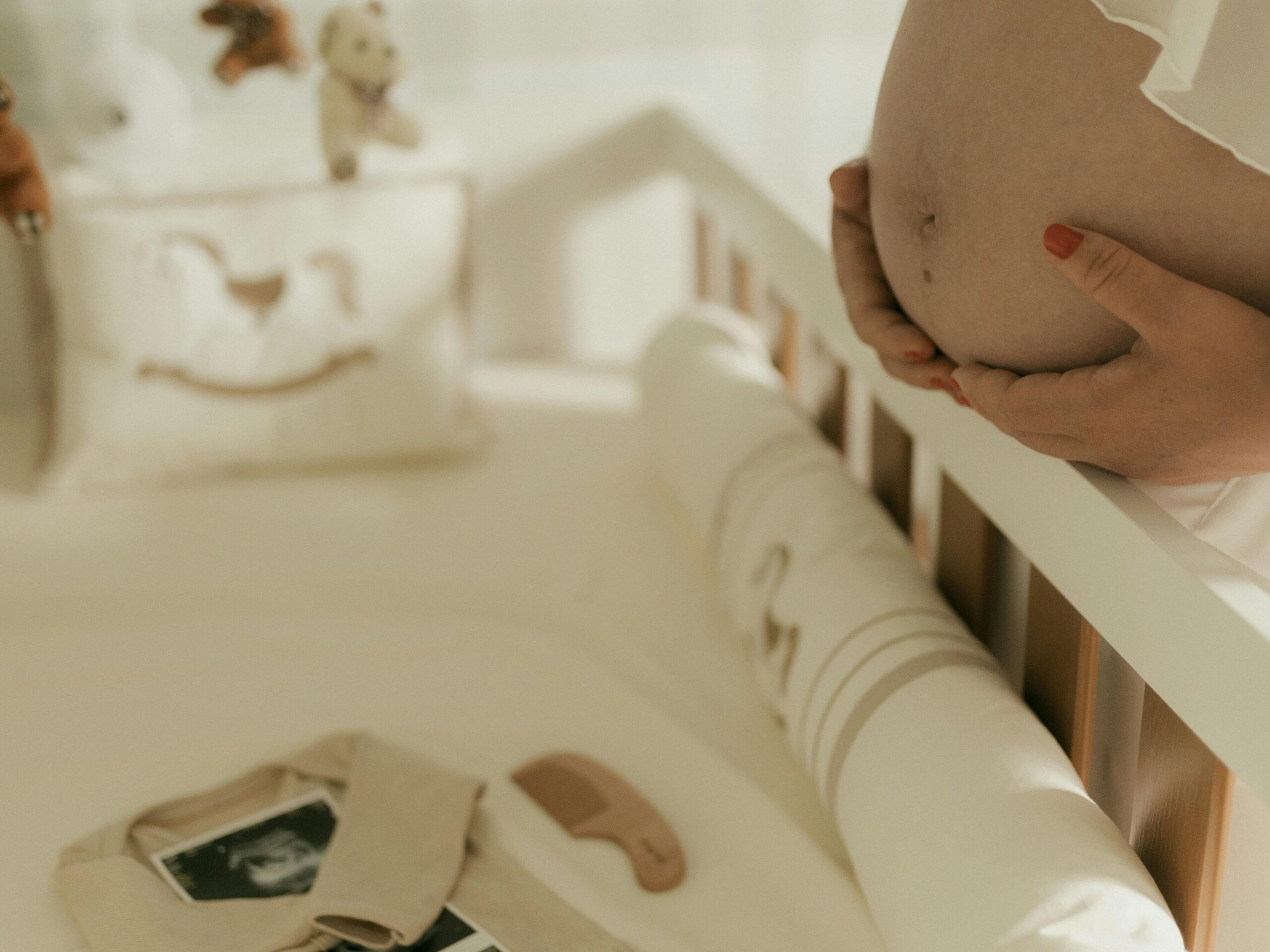 Pregnant woman adorably arranges a cozy nursery with baby care essentials and ultrasound photos.